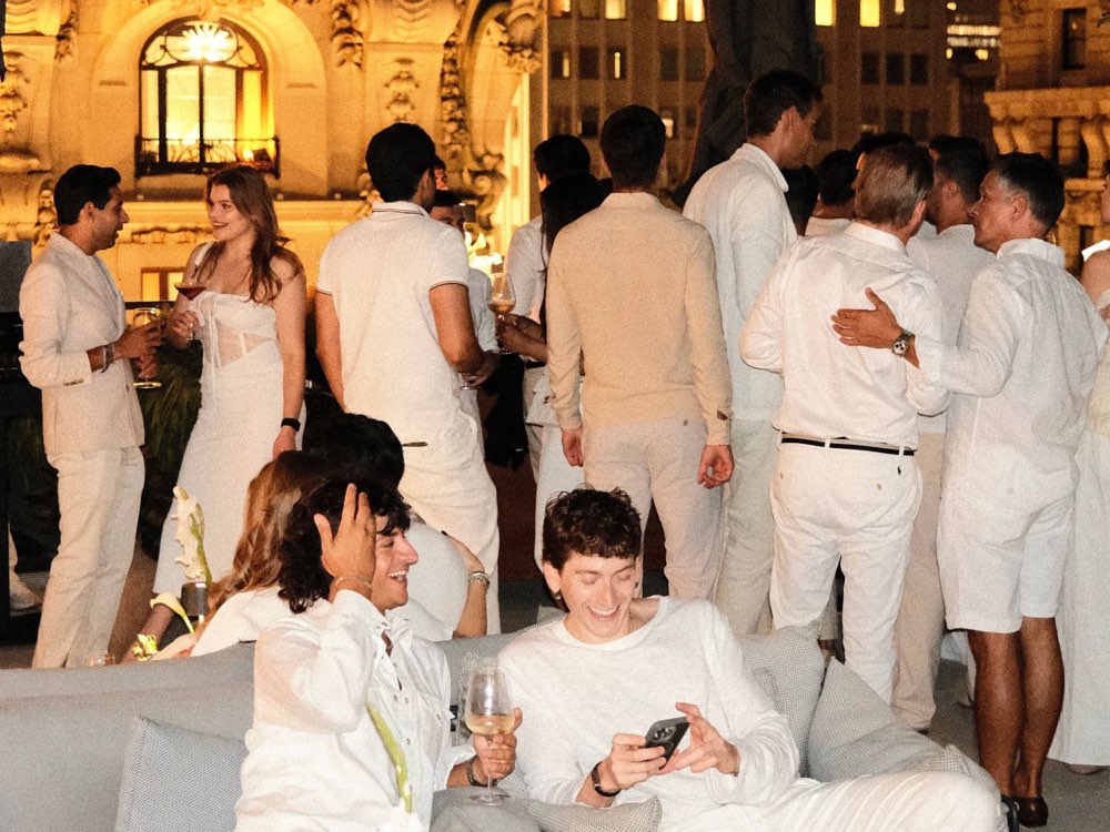 Members dressed in white at a rooftop party